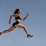 Athletic woman in motion leaping across the sky demonstrating energy and fitness outdoors.
