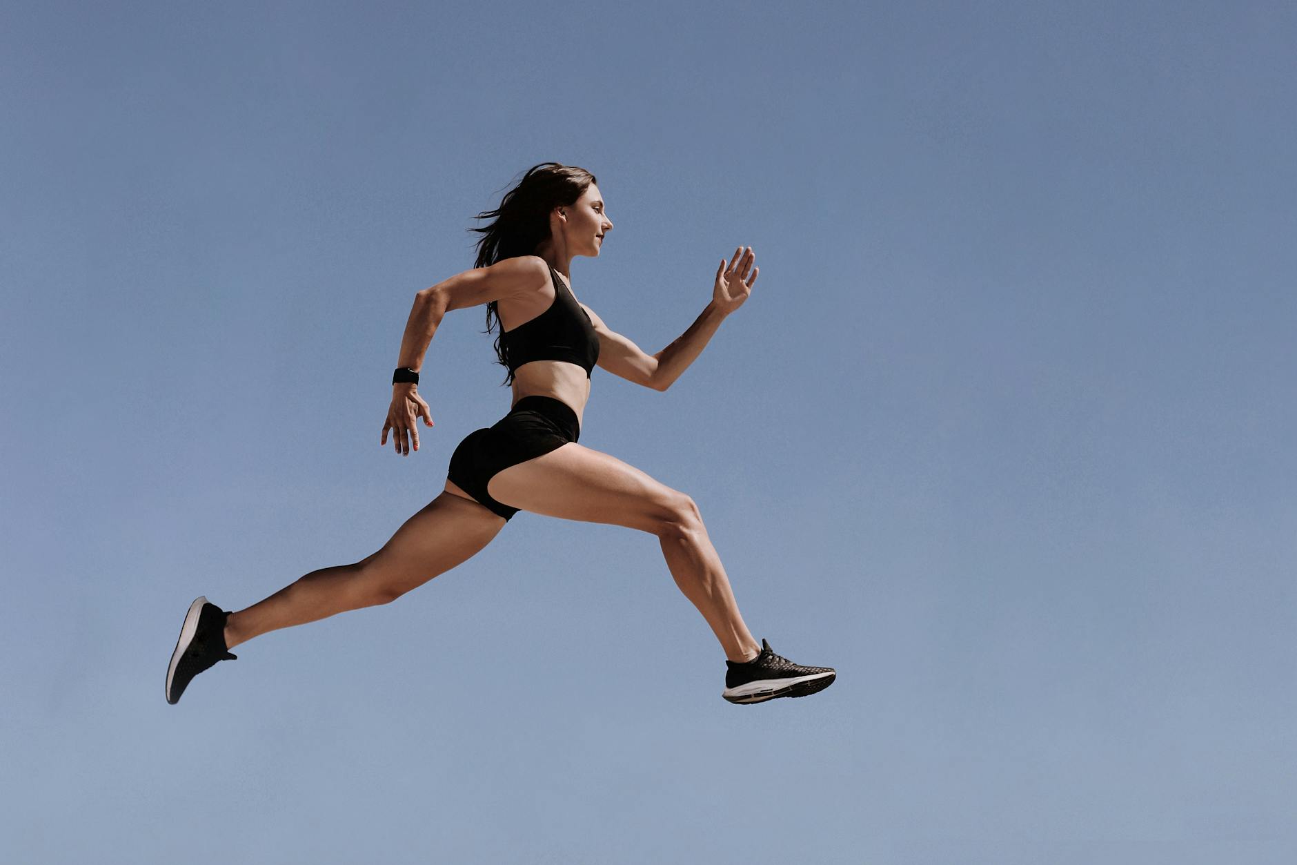 Athletic woman in motion leaping across the sky demonstrating energy and fitness outdoors.